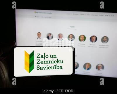 Stoccarda, Germania - 07‑28‑2025: Persona con smartphone con logo del party Zalo un Zemnieku Savieniba (ZZS) sullo schermo di fronte al sito Web. Foto Stock