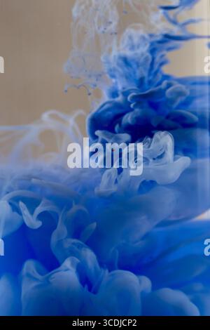 Inchiostro blu che scorre nell'acqua, creando motivi e forme artistiche Foto Stock