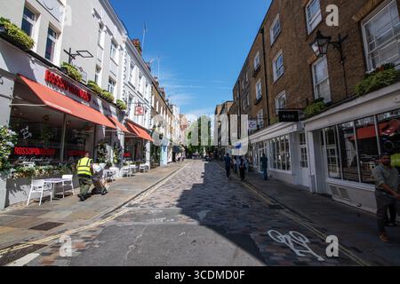Soleggiata giornata estiva su Monmouth Street, Londra, guardando verso Seven Dials, con strade affollate, negozi, pedoni e una vivace vita urbana in un centro storico Foto Stock