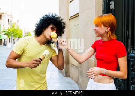 Una giovane coppia condivide i coni del gelato in un giorno d'estate Foto Stock