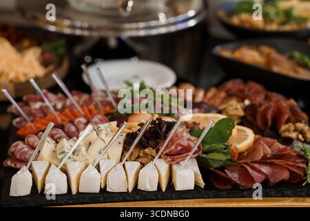 Un banco di salumi splendidamente allestito carico di prosciutto, vari formaggi, carote colorate, erbe fresche e noci è presentato in un'esclusiva mostra Foto Stock