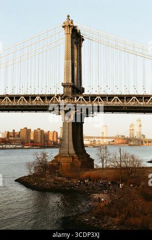 Il ponte di Manhattan immerso nella luce dell'ora dorata, catturato nel film Kodak Gold per un caldo bagliore nostalgico. Foto Stock