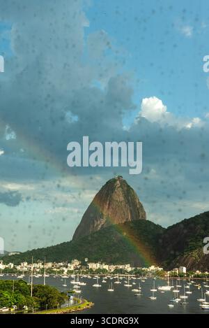 Arcobaleno sopra il Pan di zucchero visto da Botafogo attraverso il vetro piovoso - Rio de Janeiro, Brasile Foto Stock