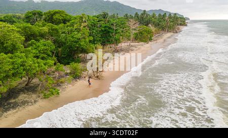Una tranquilla vista sulla spiaggia di Palomino, la Guajira, Colombia, caratterizzata da vegetazione lussureggiante e dolci onde. Foto Stock