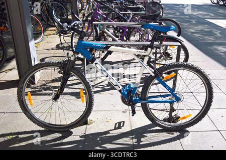 Fahrradparkplatz vor einem Supermarkt. GT Tempest, GT Bike, Mountainbike - Made in USA. GT Bicycles Inc, steht für die Initialen des Gründers Gary Turner. Er War in Seinen Anfängen ein amerikanischer Fahrradhersteller. Die Marke gehört inzwischen zum kanadischen Mischkonzern Dorel Industries *** Parcheggio biciclette di fronte a un supermercato GT Tempest, GT Bike, mountain bike made in USA GT Bicycles Inc, sta per le iniziali del fondatore Gary Turner era un produttore di biciclette americano nei suoi primi giorni il marchio ora appartiene al conglomerato canadese Dorel Industries Foto Stock