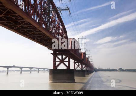 Pabna, Bangladesh - 27 novembre 2022: Vista delle audaci travi rosse dell'Hardinge Bridge sullo sfondo del fiume Padma e di un cielo parzialmente nuvoloso. Foto Stock