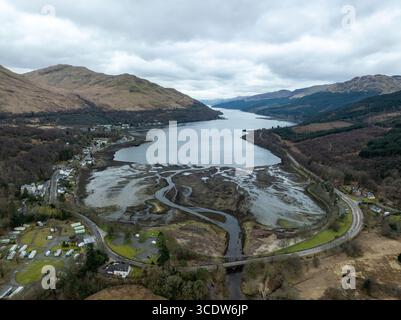 Vista aerea dei tortuosi corsi d'acqua che incontrano le tranquille acque del lago, incorniciate dalle aspre colline dai toni marrone sotto un cielo tenue, Loch Goil, Scozia, ONU Foto Stock