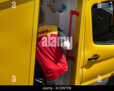 DHL Paketfahrer bei der Auslieferung. DHL Foto Stock