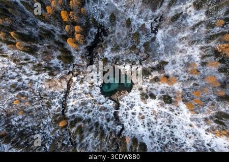 Vista aerea del lago turchese circondato da foreste innevate e cime dorate nel cuore di un paese delle meraviglie invernali, la Repubblica di Altai, Russia. Foto Stock