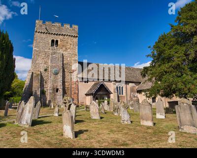 Lydbury North, UK - 08 agosto 2025: St Michael & All Angels del XII secolo, chiesa parrocchiale classificata di grado i a Lydbury North, Shropshire, Inghilterra, incorniciata da lapidi intemperie sotto un cielo estivo luminoso. Foto Stock