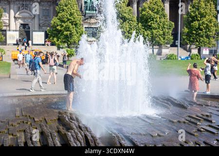 Sommerhitze a Berlino. Deutschland, Berlino 14. Agosto 2025: Abkühlung von der Sommerhitze 34 Grad Celsius im Schatten am Springbrunnen vor dem Berliner Dom. Ein Mann streckt seinen Kopf mit freiem Oberkörper in der Fontaine am Springbrunnen. *** Caldo estivo a Berlino Germania, Berlino il 14 agosto 2025 rinfrescandosi dal caldo estivo di 34 gradi Celsius all'ombra della fontana di fronte alla cattedrale di Berlino Un uomo si allunga la testa con il corpo superiore esposto nella fontana della fontana Foto Stock