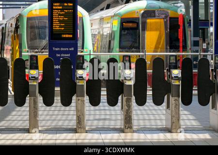 Londra, Inghilterra, Regno Unito - 4 luglio 2025: Barriere automatiche alla stazione ferroviaria di London Bridge con treni pendolari sullo sfondo Foto Stock