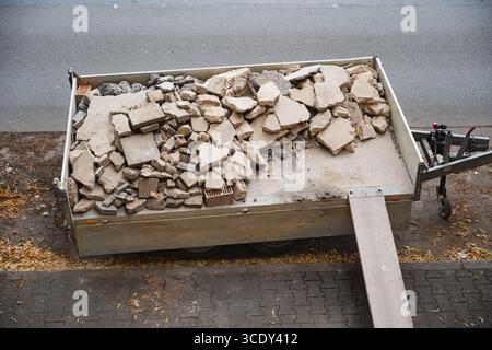 Un mucchio di macerie e detriti riempie un rimorchio parcheggiato sulla strada Foto Stock