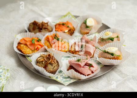 Una selezione splendidamente organizzata di tartine con salmone affumicato, prosciutto e salati spalmabili, perfetti per riunioni o feste eleganti. ideale per applicazioni Foto Stock