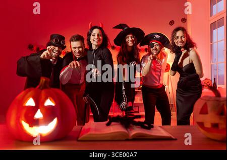 Festa di ritrovo per la festa di Halloween, amici in posa in costumi spaventosi di vampiro, strega, diavolo Foto Stock
