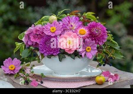 composizione floreale di rosa, dahlia, ortensie in fiore e anemoni giapponesi in una barca per salsa Foto Stock