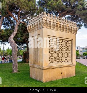 Baku, Azerbaigian - 4 maggio 2024: Struttura in pietra con motivi geometrici ornati e tetti decorativi nel parco Nizami. Circondato da lussureggianti prati e alberi verdi Foto Stock