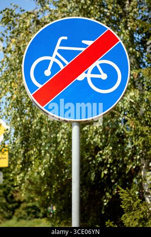Segnaletica circolare blu con una linea diagonale rossa sopra il simbolo di una bicicletta, che indica la fine di una pista ciclabile o di un percorso ciclabile designato. Utilizzato per informare cy Foto Stock