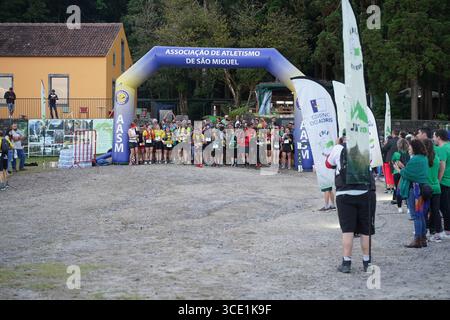 I corridori si riuniscono alla linea di partenza della mini gara di trail durante l'evento Furnas Night Trail, pronti a lanciarsi nella sfida notturna. Foto Stock