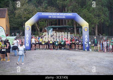 I corridori si riuniscono alla linea di partenza della mini gara di trail durante l'evento Furnas Night Trail, pronti a lanciarsi nella sfida notturna. Foto Stock