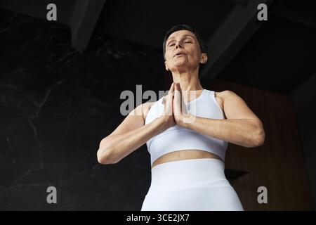 Ritratto di donna caucasica anziana che pratica Yoga Meditazione in casa Foto Stock
