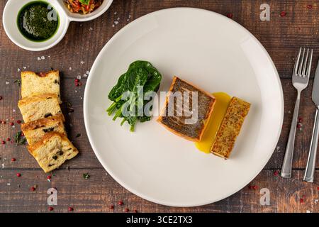 Filetto di salmone scottato servito con spinaci saltati e croquette di patate Foto Stock