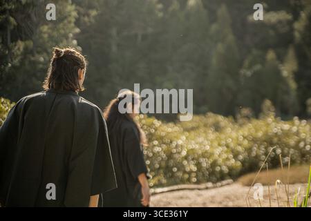 Un samurai in kimono nero sta camminando attraverso la foresta. Foto Stock
