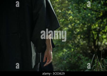 Un samurai in kimono nero sta camminando attraverso la foresta. Foto Stock