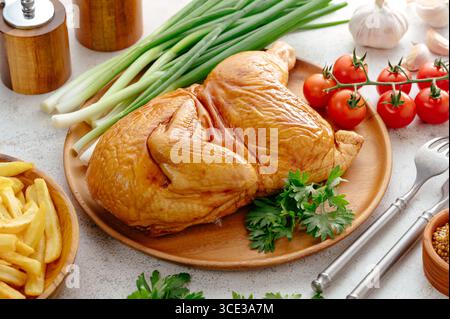pollo affumicato su un asse di legno con erbe e verdure Foto Stock