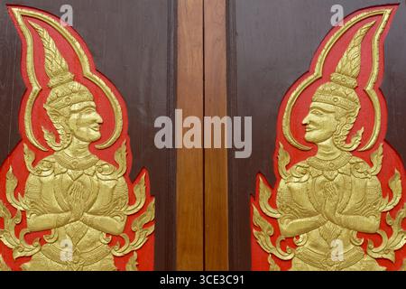 Una porta in un tempio nella città di Phuket, Thailandia, che mostra due esseri celesti maschi chiamati Gandharvas, che eseguono il tradizionale saluto thailandese, il Wai Foto Stock
