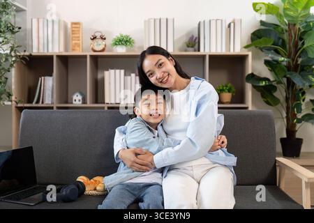 Caldo abbraccio. Una madre e un figlio condividono un abbraccio amorevole sul divano. Foto Stock