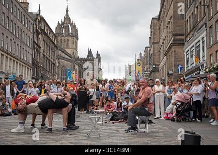 Edimburgo, Sotland, Regno Unito. 15 agosto 2025. Festival Fringe Day 15 è caldo ma coperto, la temperatura è di 22 gradi centigradi per i visitatori e gli artisti di strada. Nella foto: Brucie dall'Australia ha i suoi oulunteers che levitano a Royal Mile. Credito: Arch White/alamy notizie dal vivo. Foto Stock