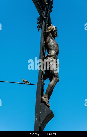 Una scultura dettagliata raffigurante Gesù su una croce si erge contro un cielo blu brillante. Puy de Dome, Alvernia Rodano Alpes, Francia Foto Stock