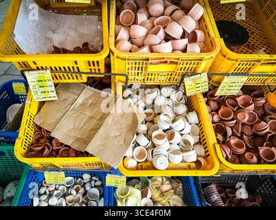 Un assortimento di piccole pentole di diya indiana tradizionali in argilla o lampade a olio esposte in casse di plastica gialle in un mercato indiano Little india malesia Foto Stock