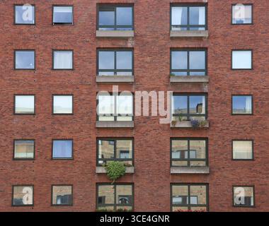 Parte di un moderno edificio di appartamenti in mattoni rossi con diversi tipi di finestre (Copenhagen, Danimarca) Foto Stock