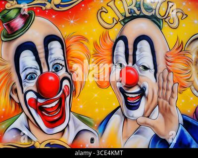 Due allegri clown, uno con un cappello verde e l'altro che ondeggia, sono ritratti in colori vivaci su sfondo giallo, Francia Foto Stock