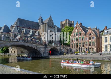 Tour in barca con i turisti sul fiume Lys / Leie lungo il Korenlei, il ponte di San Michele e la chiesa nella città di Gand in estate, nelle Fiandre orientali, in Belgio Foto Stock