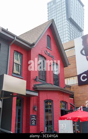 Un edificio in mattoni rossi a Yorkville ospita l'Oxley, con finestre con finiture nere e cartelli sopra la porta e sul muro d'angolo del patio. Foto Stock