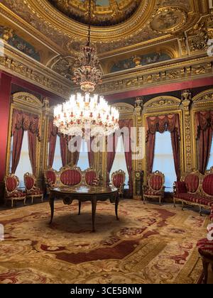 Sontuosa sala del Palazzo Dolmabahce a Istanbul, con lampadario di cristallo, sedie in velluto rosso, decorazioni dorate e ricchi tappeti. Foto Stock