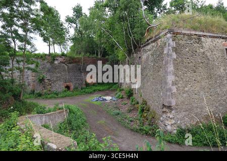 Cortile interno della fortezza di Owcza Góra a Kłodzko con mura in pietra, ingressi ad arco e vegetazione forestale Foto Stock