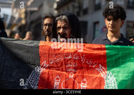 Madrid, Spagna. 15 agosto 2025. I manifestanti detengono una bandiera afghana durante una manifestazione alla Puerta del Sol di Madrid per i diritti delle donne afghane. Il 15 agosto ricorre il quarto anniversario della cattura di Kabul da parte dei talebani, un evento che ha segnato il loro ritorno al potere in Afghanistan dopo il ritiro delle truppe statunitensi e della NATO. Da allora, la situazione del paese ha subito un drastico declino, soprattutto in termini di diritti umani. Credito: SOPA Images Limited/Alamy Live News Foto Stock