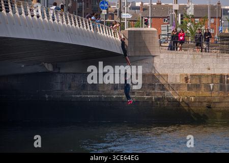 Un ragazzo pendenti da Samuel Beckett Bridge come un altro cade nel fiume Liffey, Nord Dock, Dublino, Leinster, Irlanda Foto Stock