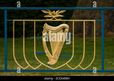 Dorato arpa celtica che rappresenta lo stemma di Irlanda è parte di un ferro battuto recinto nel Giardino della Rimembranza, Parnell Square, Dublino, Lein Foto Stock