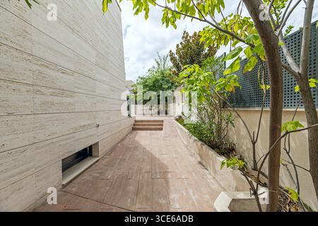 Casa singola di design con una facciata in marmo bianco sporco e un passaggio pedonale circostante con illuminazione a soffitto Foto Stock