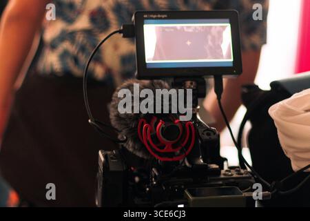 Dietro le quinte di una produzione audiovisiva, registrando film e monitorandoli attraverso schermi e telecamere. Del direttore e del team di produzione Foto Stock