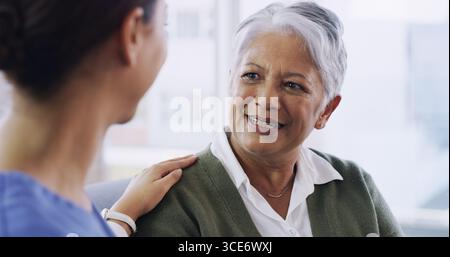 Supporto, infermiera e sorriso con la donna anziana sul divano per l'empatia, terapista occupazionale e medico. Consulenza sanitaria, discussione e paziente anziano con Foto Stock