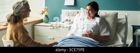 Donna caucasica di mezza età che conforta la giovane figlia incinta in clinica Foto Stock