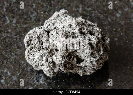 Assaggio di ruvida roccia pomice su fondo di granito nero da vicino dalla Sicilia Foto Stock