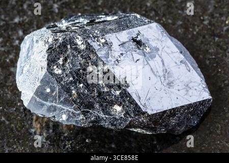 Assaggio di grezzo cristallo di granato nero melanite andradite su sfondo di granito nero da vicino dal Kazakistan Foto Stock