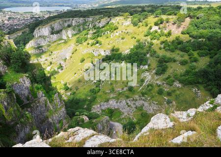Vista dalla cima della gola di Cheddar con il villaggio di Cheddar e il suo riservista in lontananza. Somerset Foto Stock